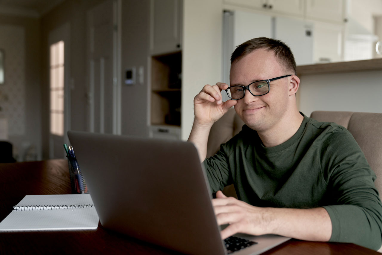 Erwachsener mit Down-Syndrom mit Laptop